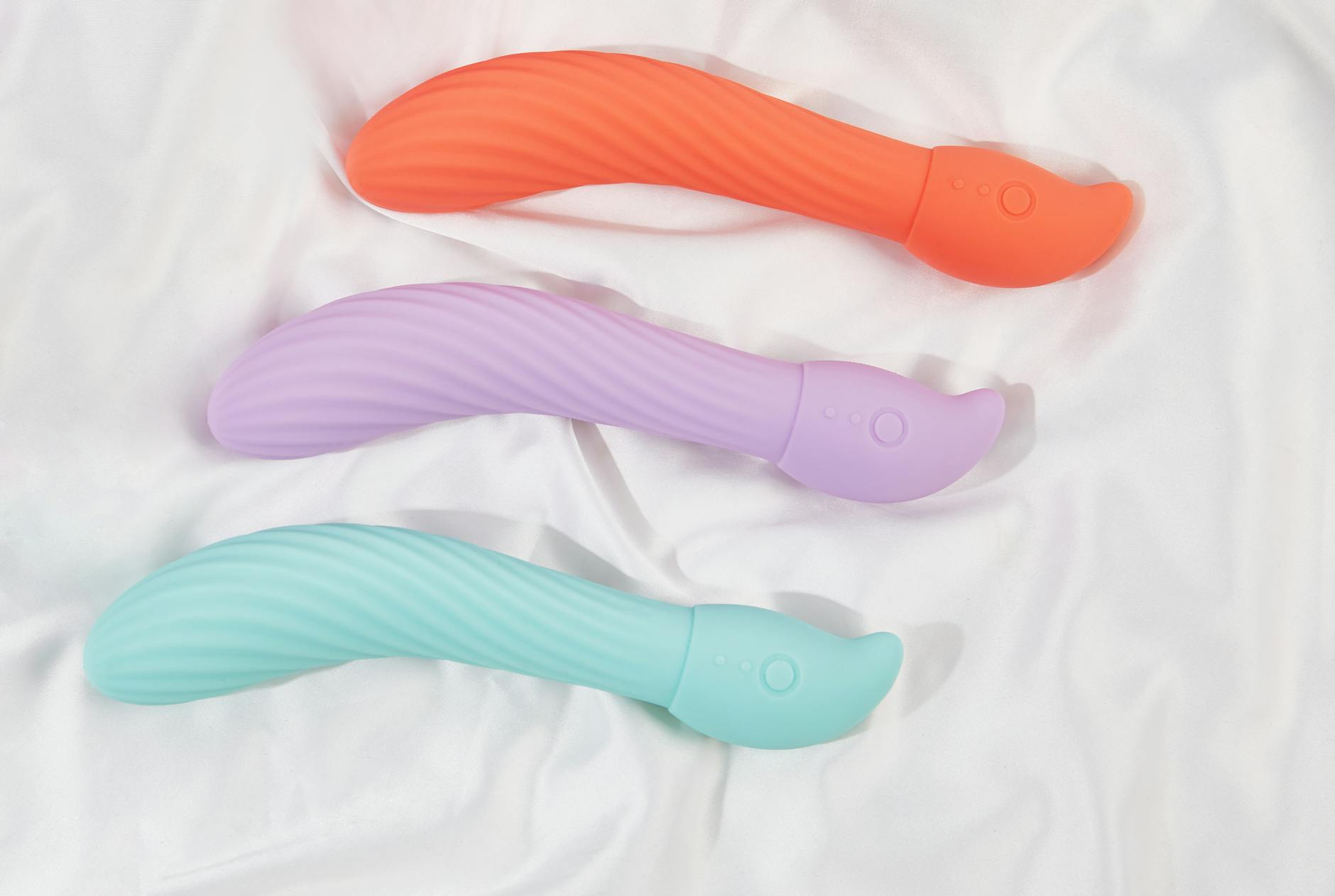 Three colorful vibrators on white fabric, showing smooth texture and design