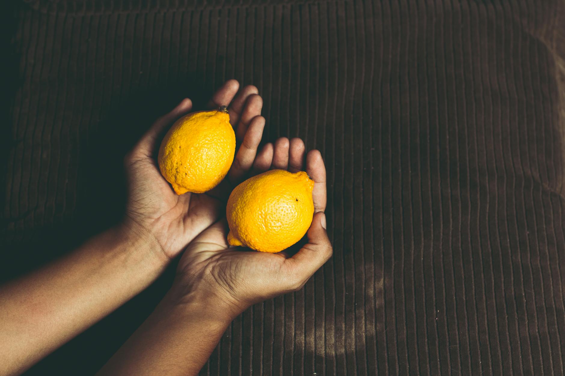Two fresh lemons held gently in cupped hands, symbolizing tender, pressure-free touch.