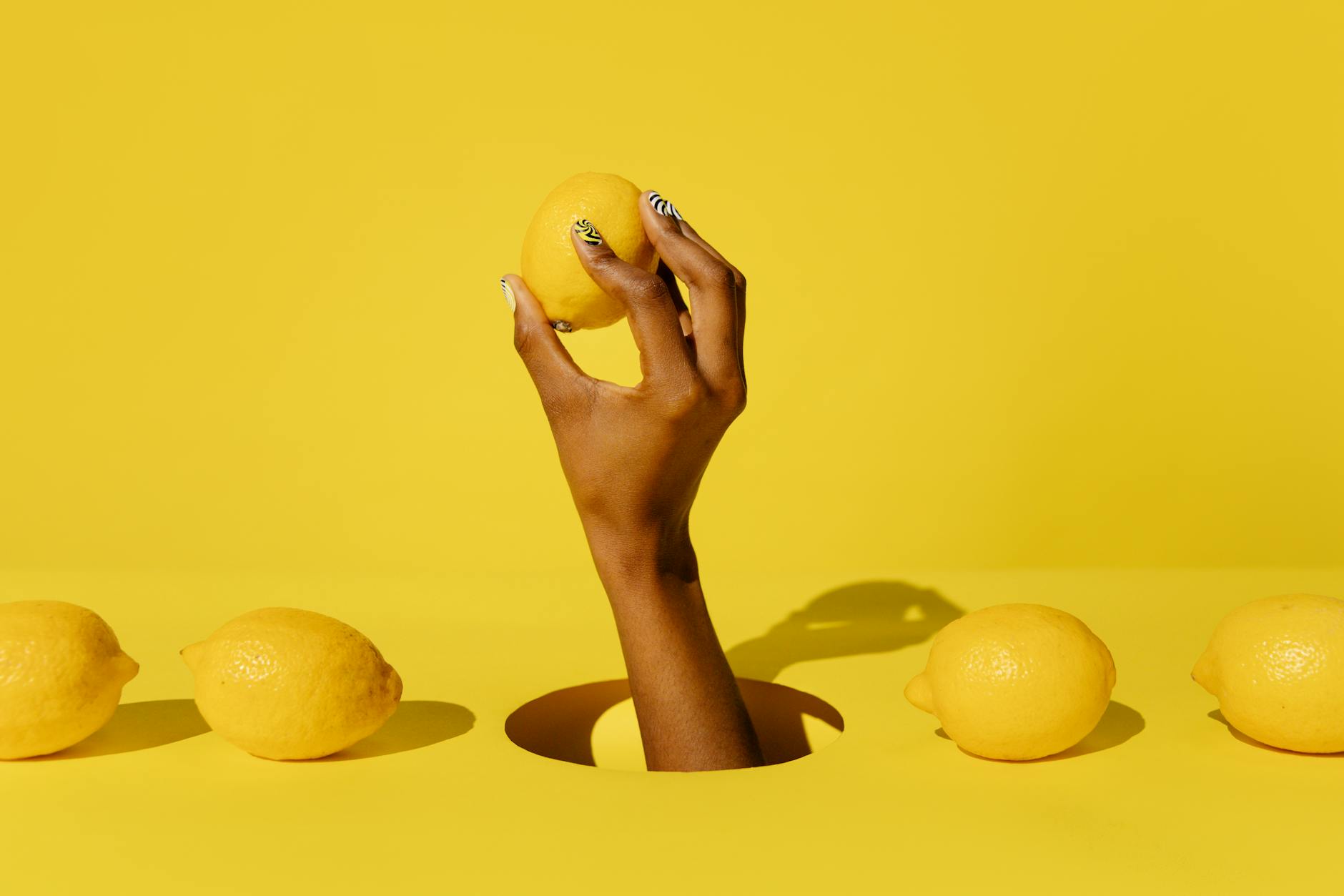 Hand holding a fresh lemon against a bright yellow background, symbolizing the renewal of sensation after hormonal changes