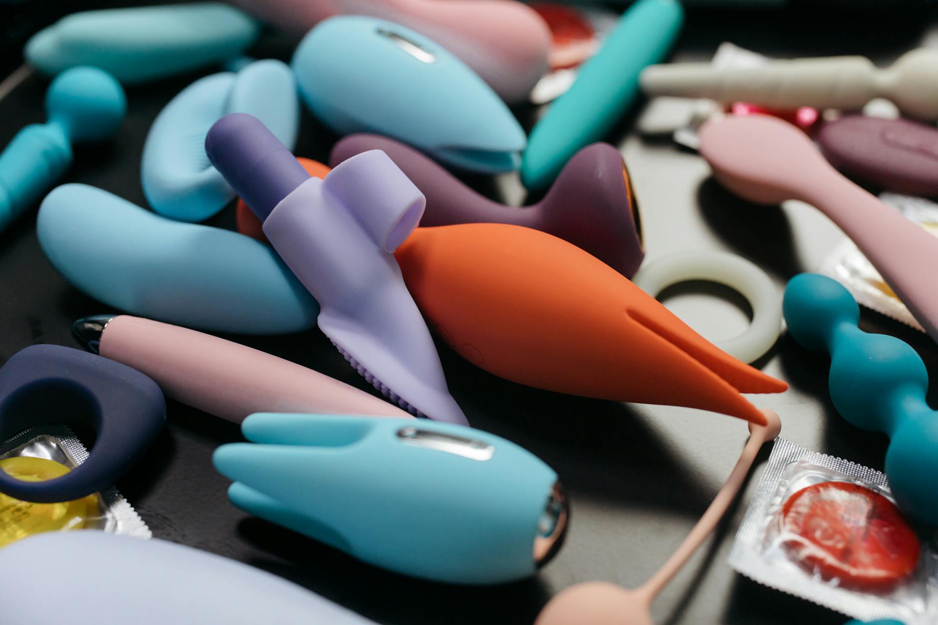 Woman holding colorful clitoral vibrators in thoughtful expression