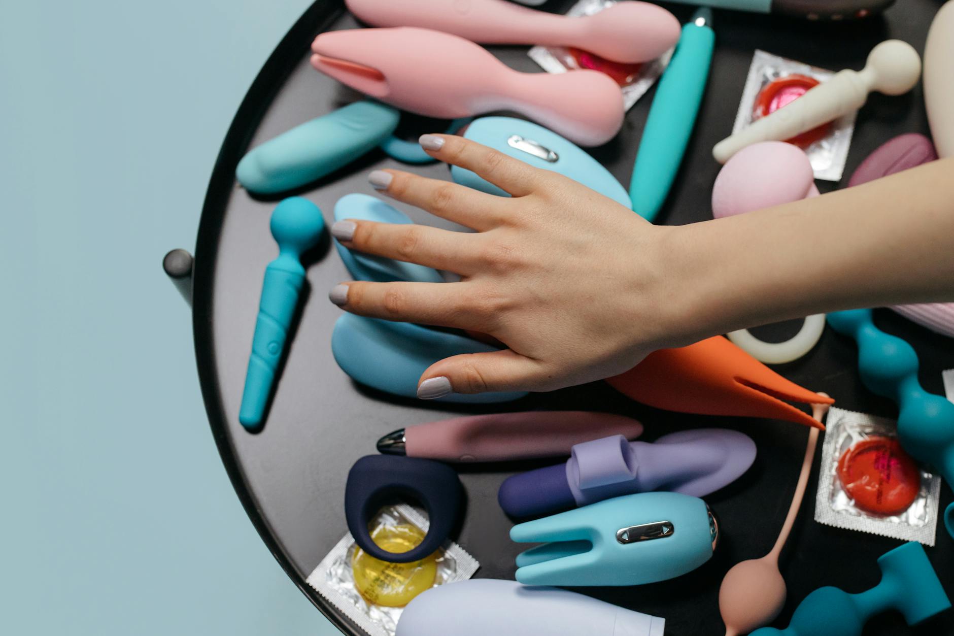 A close-up of a hand holding a blue suction vibrator above a decorative glass bowl