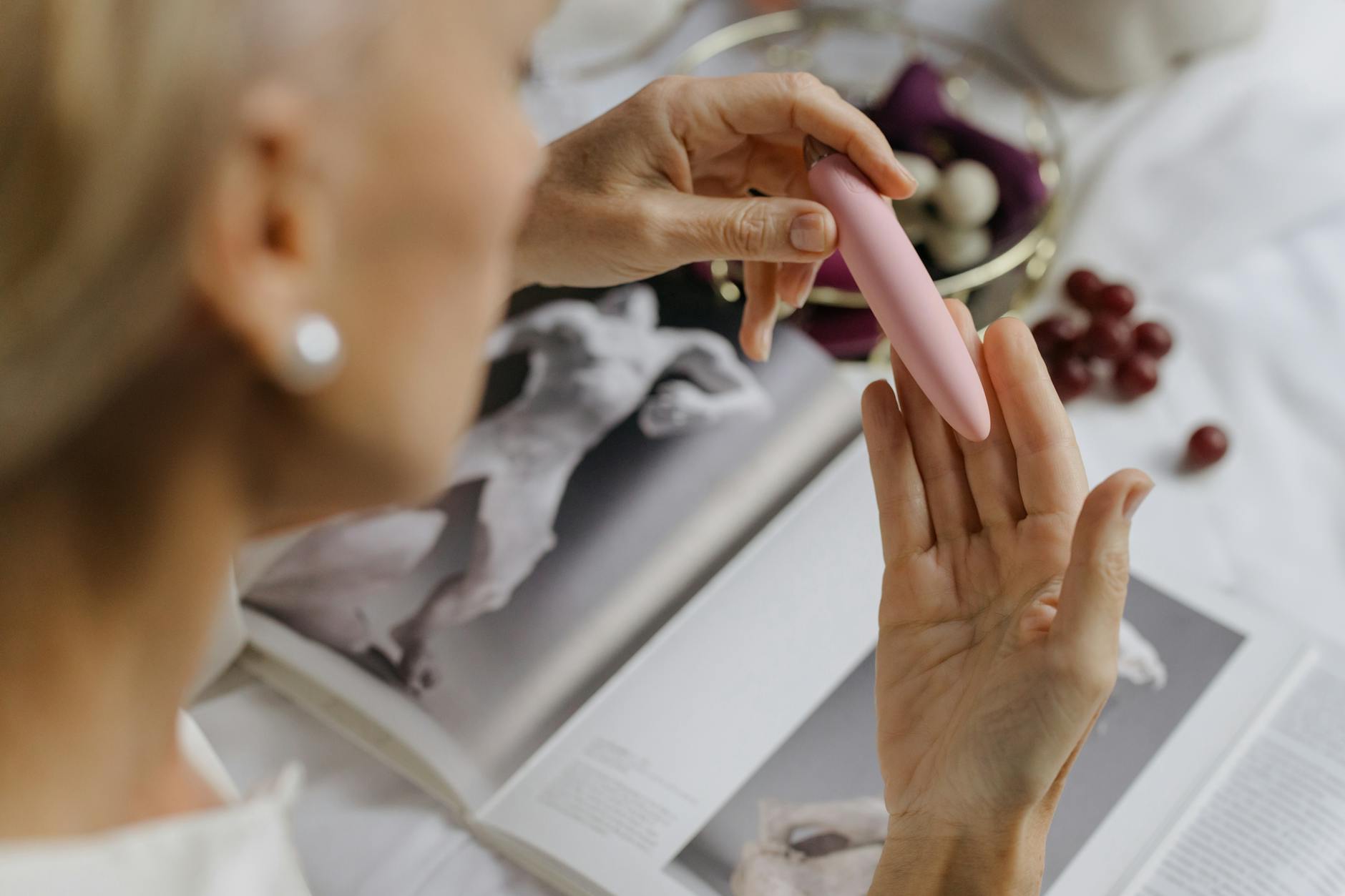 Woman holding a pink vibrator with personal wellness items in the background, representing intimate reconnection after stress.